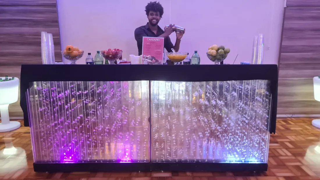 Bartender preparando drinks atrás de um balcão iluminado