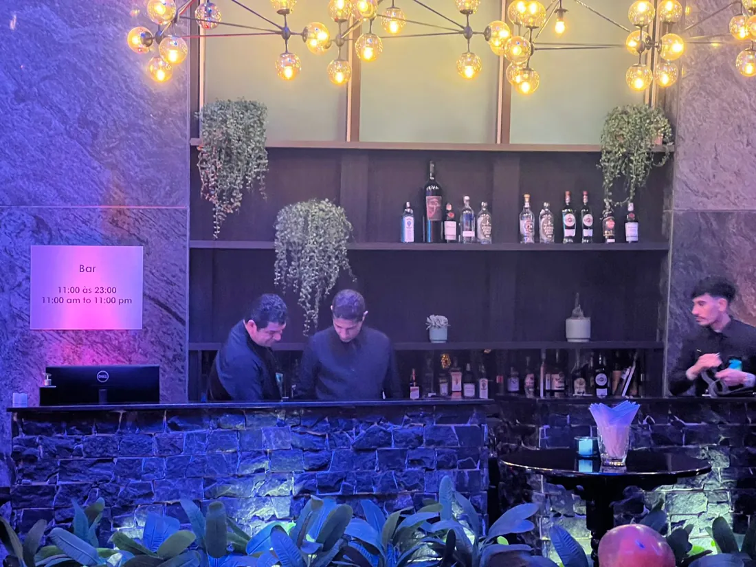 Bartenders atrás do balcão com a estante de bebidas iluminada