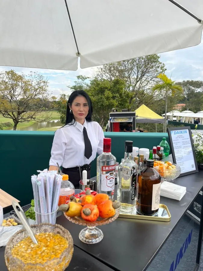 Bartender uniformizada preparando drinks em evento ao ar livre